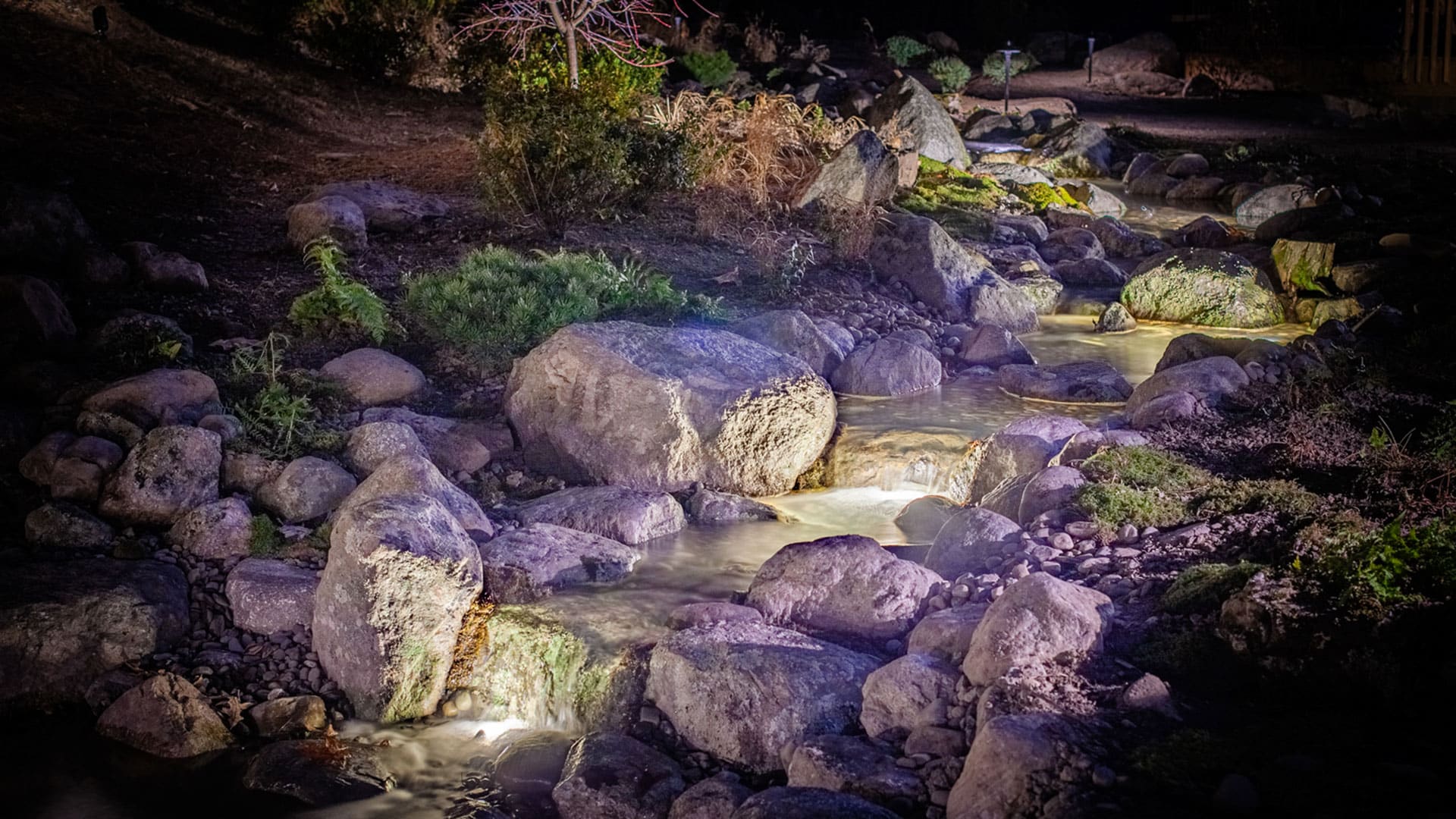 Pondless waterfall at dusk with landscape lighting
