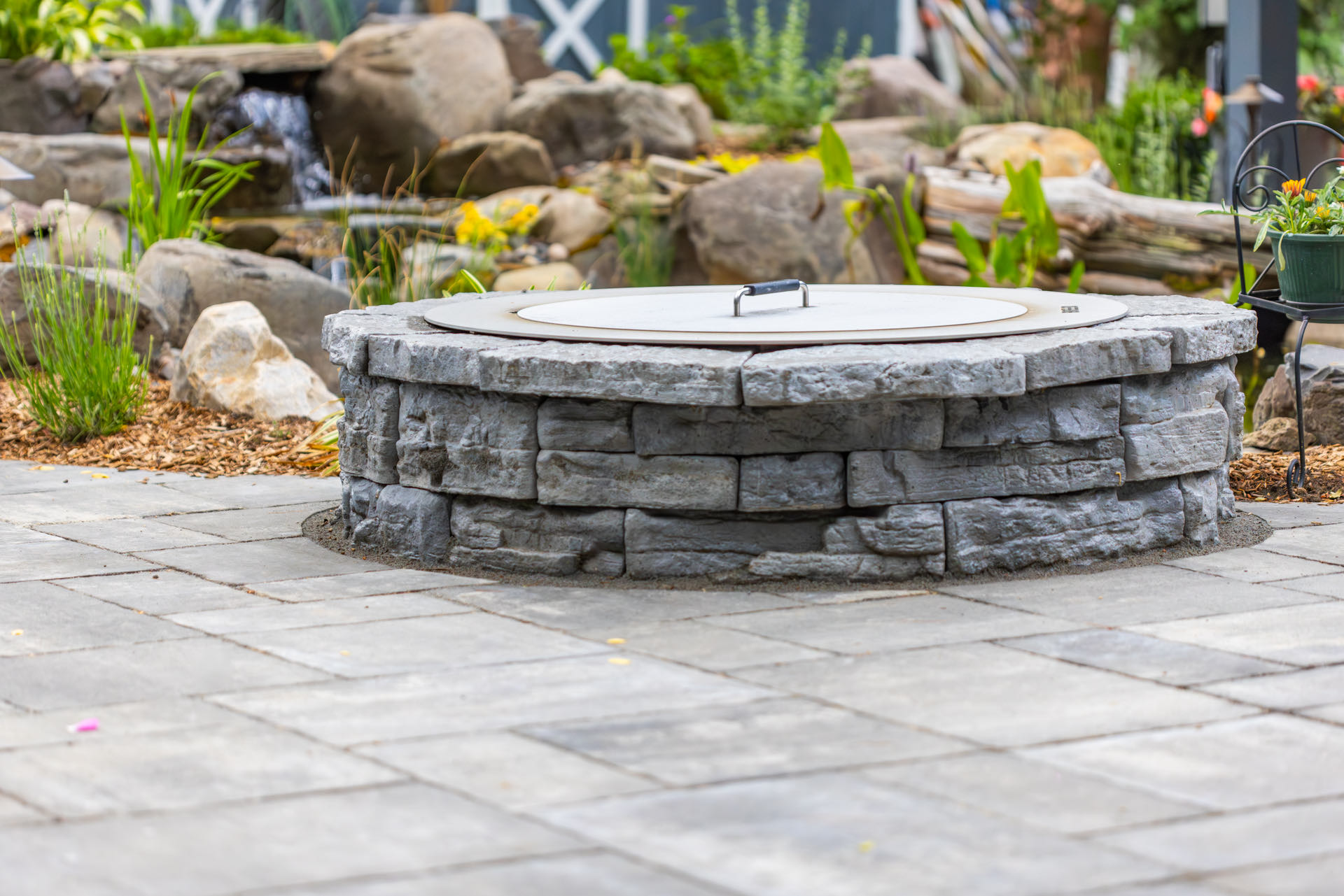 Stacked-stone fire pit with the pond and waterfall beyond