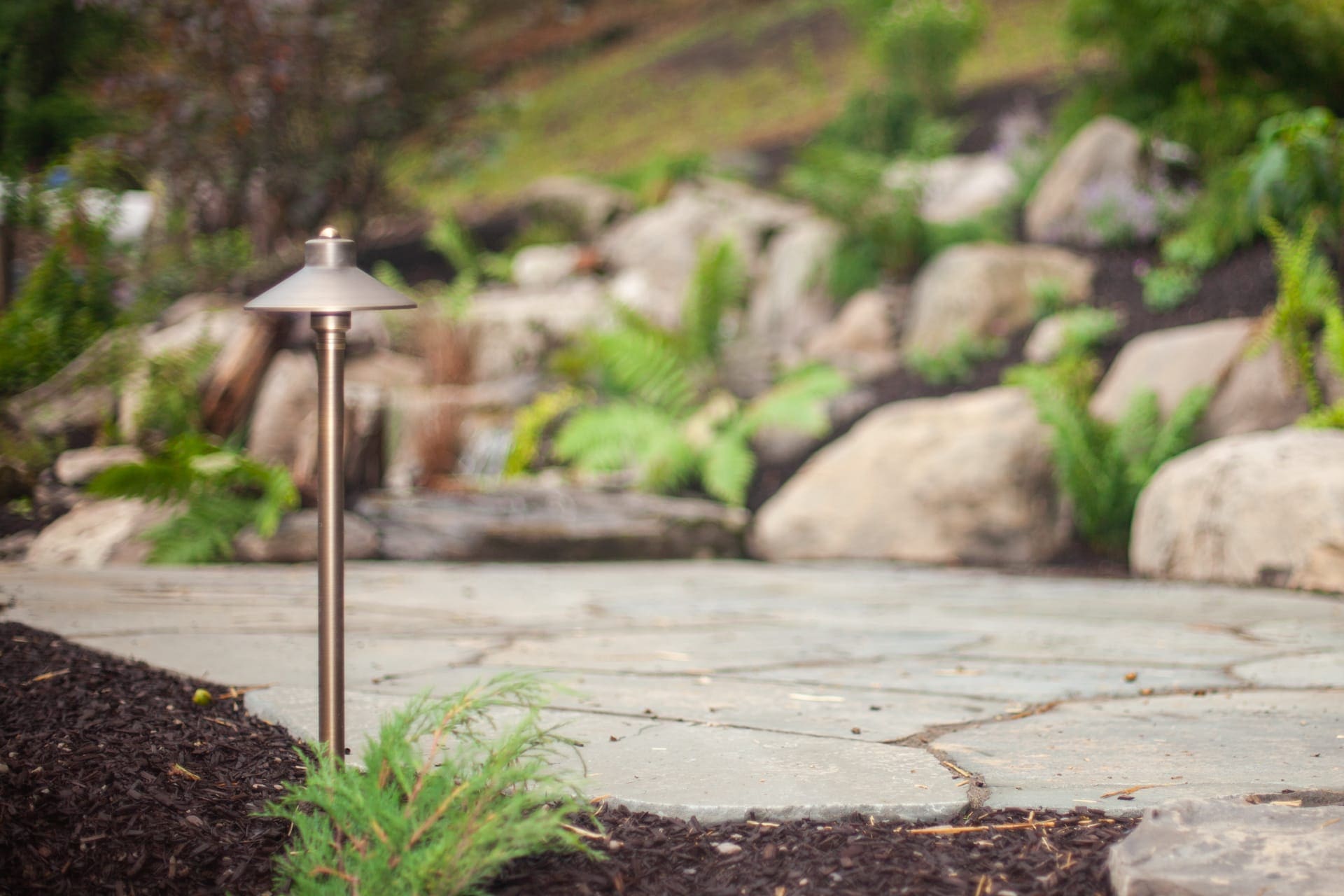 Flagstone patio with path lighting and boulder waterfall